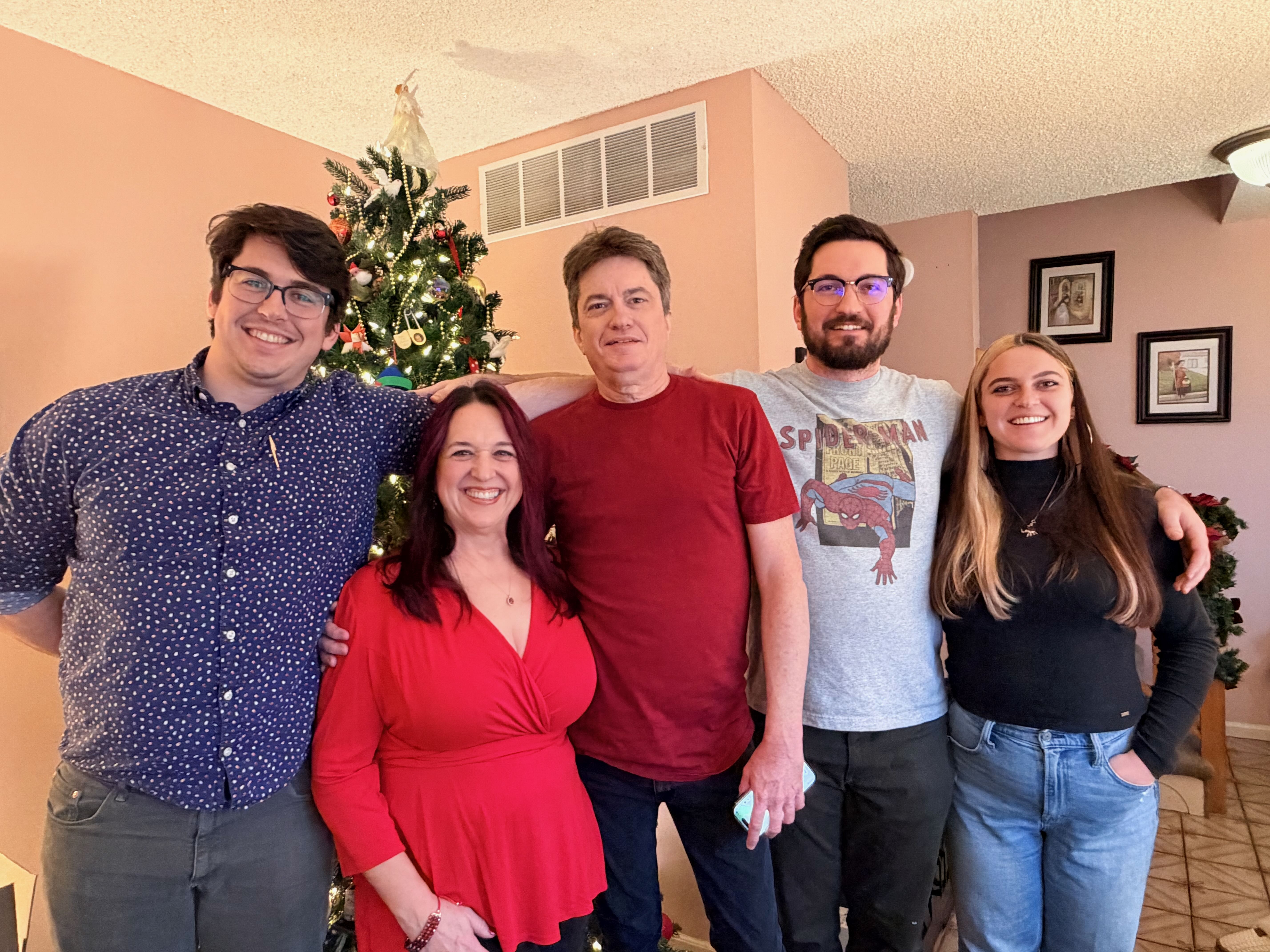 Family photo of Steve with family members in front of a decorated tree.